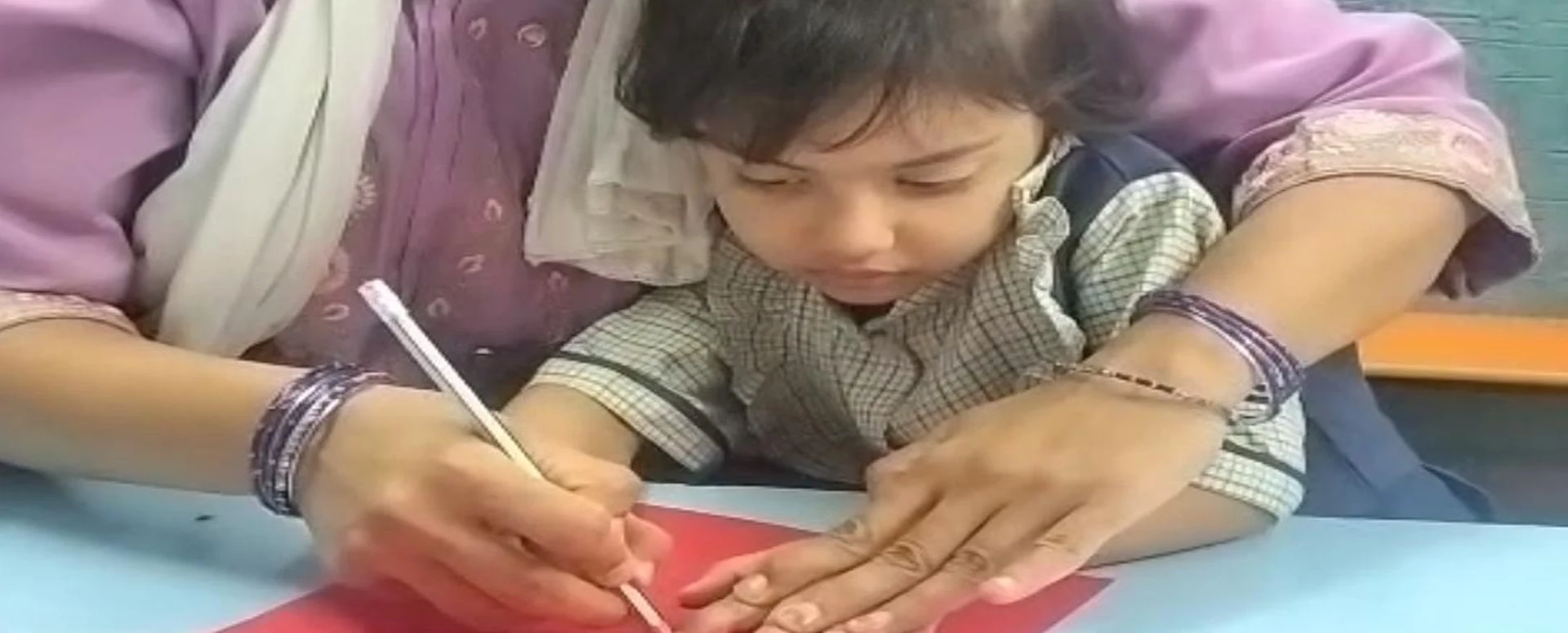 Teacher guiding a child during a creative classroom activity at Happy Scholar School in Mehdipatnam